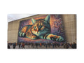 A large canvas art piece depicts a vibrant, oversized cat with mesmerizing eyes lying in front of a colorful, abstract background, displayed outdoors with a crowd of people observing it.