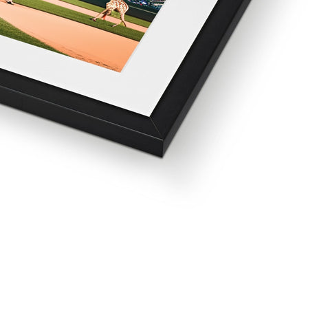 A picture frame with a baseball pitcher in a baseball field laying on the ground.