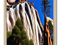 A water fall is in the background of a picture with mountains in the foreground.