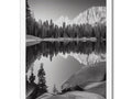 There is a black and white photo on a frame of a lake near a mountain.