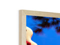 A red wooden mirror frame that is leaning next to a picture frame on a tree.