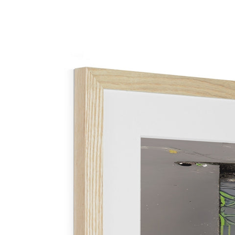 A picture frame hanging near some drywall is seen under a small picture of a wood