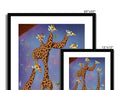 Three giraffe are standing by a large, lush green bush looking for grazing animals.