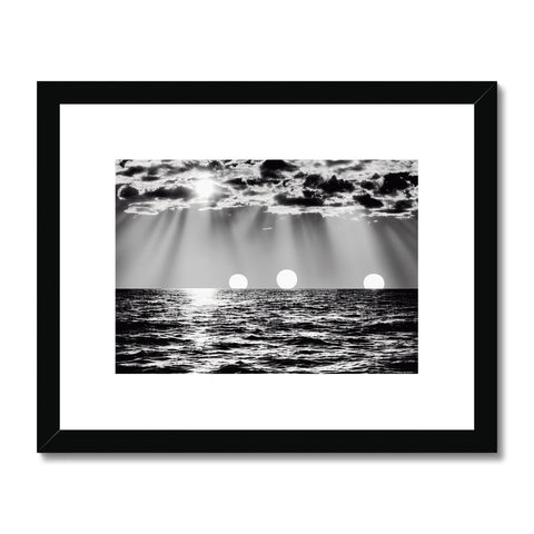 A black and white framed print of the ocean with a sailboat passing by a house