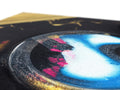 A photo of graffiti spray painting on a CD case with silver foil.