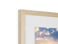 A picture framed in wood on a white paper frame and a picture of a sunset