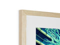 Black and white photo inside of a wood frame next to green and blue framed artwork.