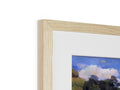 A picture frame sitting on top of a large pine table with a small blue picture on