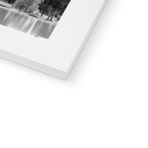 A white photo on a black photo frame is on top of a tree trunk.