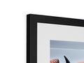 A picture frame with an image sitting in a frame with a black wall.