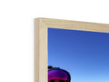 A photo is in a tall photo frame that is on top of a wooden wall.