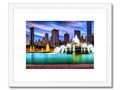 A framed photograph of the skyline of Chicago on a bookcase with a wooden frame with