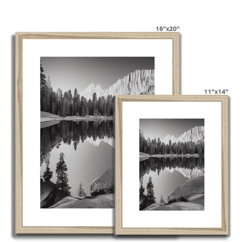 A black and white frame is sitting near two pictures with two frames.