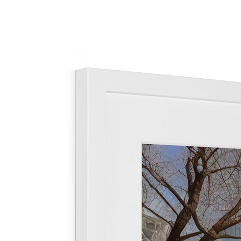 A photograph is on top of a picture frame with a white framed piece in a photo