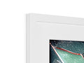 An imac is in a picture frame hanging above another picture frame.