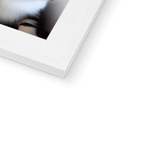 A cat peeks out of the frame of a white box in a picture frame.