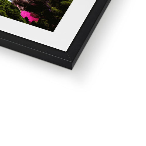 A very colorful photograph is sitting on top of a picture frame in a house.