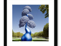 A topiary with a blue cloud on a white wall, hanging in frame