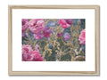 A framed art print showing pink flowers with an image of a painting sitting on a wall