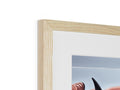 A pair of pictures sitting on a table are framed in a wooden frame.
