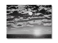 A black and white photo of the sunrise on a moonlight background with a boat.