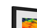a framed art image sits on top of a display with colorful prints on it