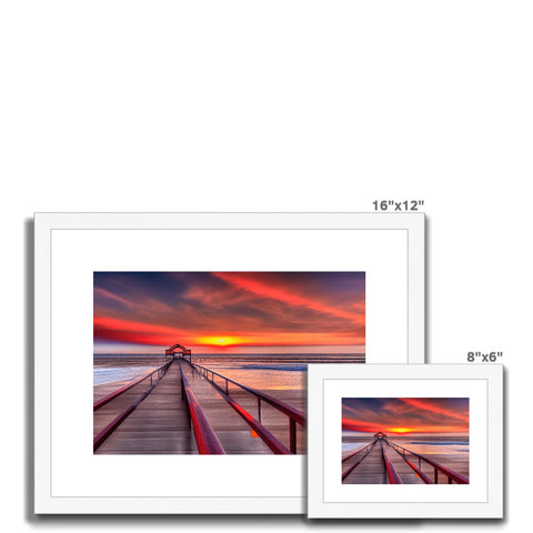 Two white picture frames filled with a sunset and a watercolor image that are on a