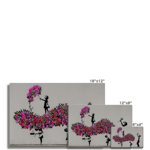 A spray painted and painted on brick wall has pink flowers and a picture of trees flowers