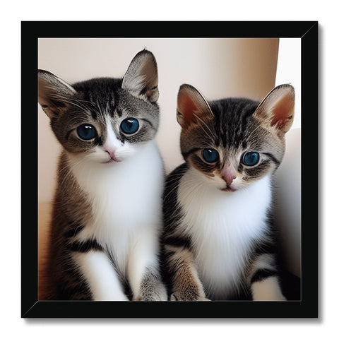 A couple of little gray kittens pose on the top of a picture frame next to