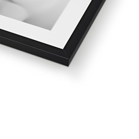 A white picture frame over a frame on a wall in dark metal.