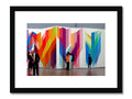 An art print hanging from a white wall surrounded with colors.