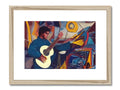 A man with a guitar stands in front of a wall mounted art print of a blue