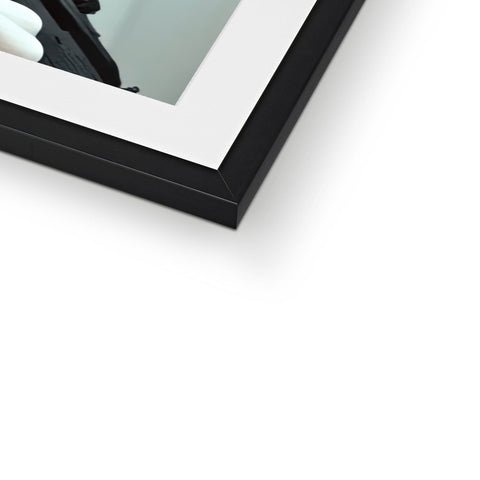 A framed picture of a camera frame on the side of a mirror on a wall.