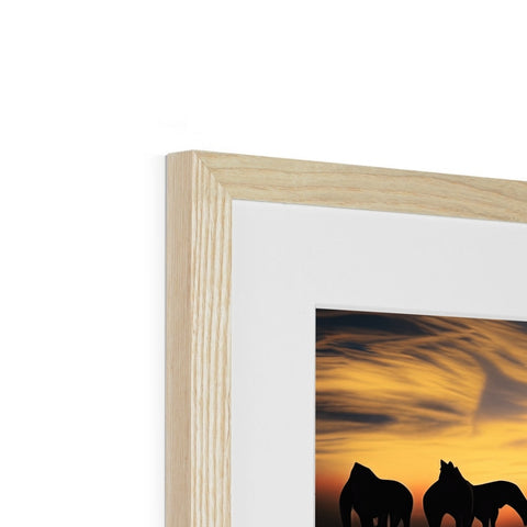 A white picture frame topped with wood holding a picture of sun setting by trees.