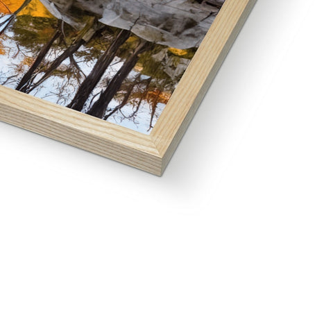 A picture is being framed in wood near a wood frame on a book.