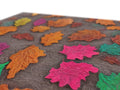 A table with a cushioned cushion with lots of colorful leaves on it.