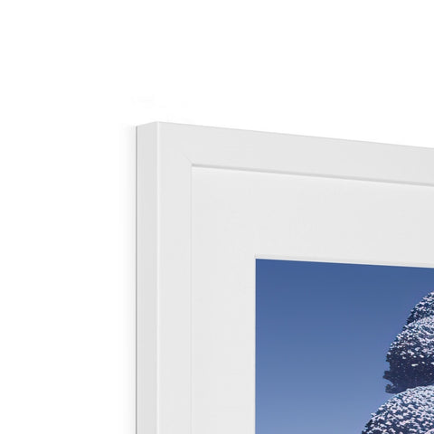 A white picture frame framed on a wall with a few blue sheets.