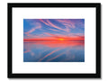 A beautiful sunset over sea in a red print framed frame with a boat.