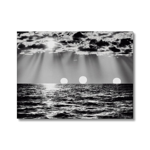 A blanket covered in black and white images of a sunset with large sun rays.