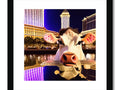 A large white framed picture of a cow standing in a plaza in Las Vegas