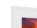 An image is in a picture frame standing in a frame with an imac on it