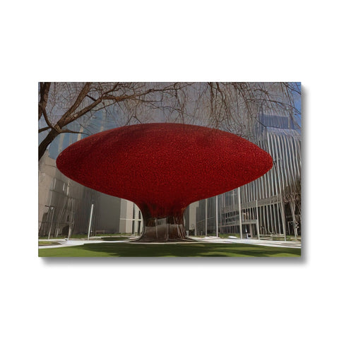 A sculpture with the shape of a red hat outside of a forest with a red tree