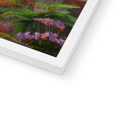 A framed picture of tropical plants sitting on a white frame.