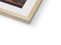 A photo of a white picture of a sunset in a wooden frame that is mounted above