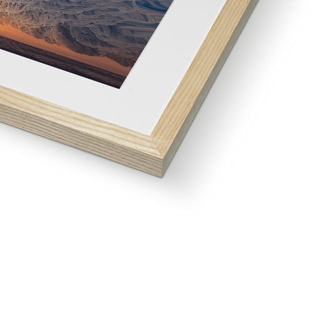 A photo of a white picture of a sunset in a wooden frame that is mounted above