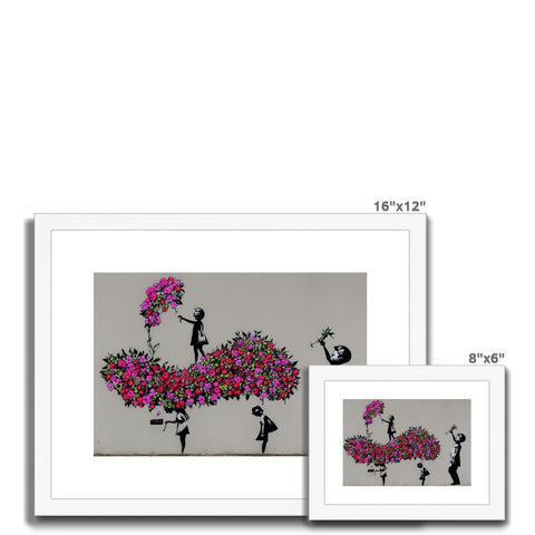 A picture of lilacs hanging on a wall next to a red and white picture frame