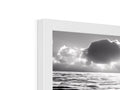 A picture frame holding a black and white photo of the ocean with a white cloud.