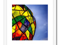 A colorful kite holding a sparkly ball of light up in a picture frame.