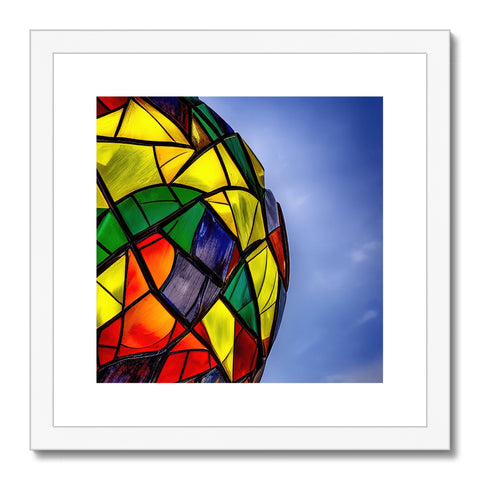 A colorful kite holding a sparkly ball of light up in a picture frame.