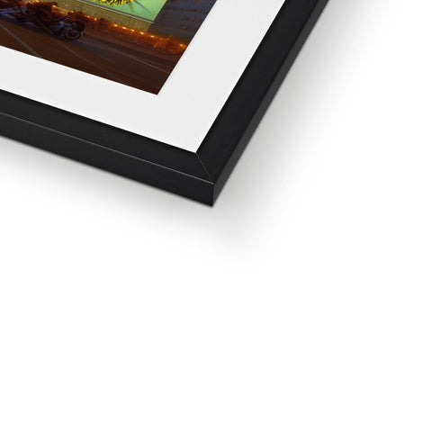 A framed image on metal plate displayed above the top of a picture frame.